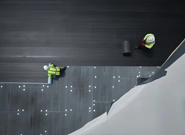 Overhead view of roofers installing tapered insulation boards on a commercial roof